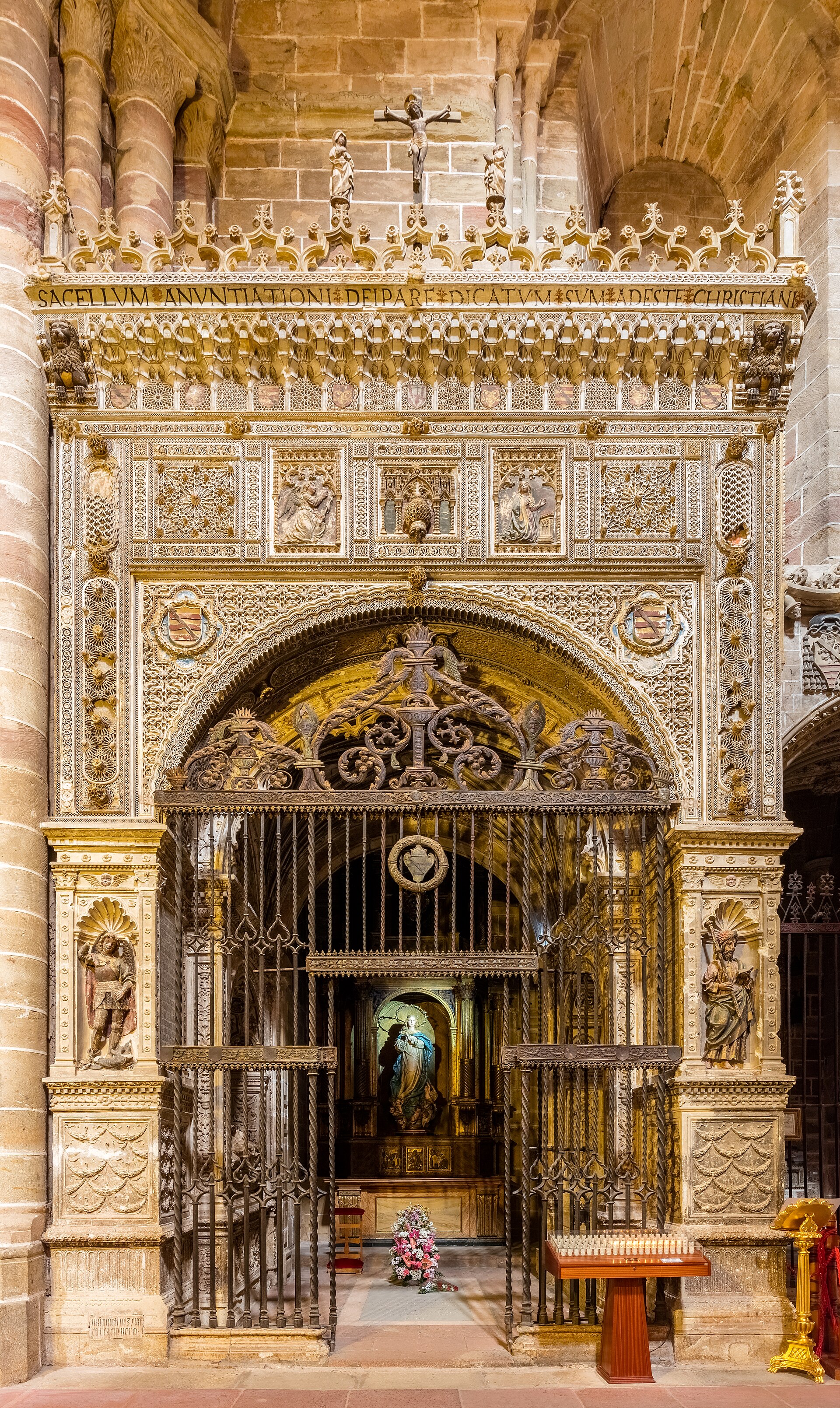 Puerta de la capilla de la Anunciación, catedral de Santa María de Sigüenza, Sigüenza, Castilla-La Mancha, España. La capilla la fundó en 1515 el vicario judicial Fernando Montemayor. El exquisito portal está decorado en estilo cisneariano y tiene imágenes de San Miguel y San Jacobo en la parte inferior, elementos mudéjares en el arco y una escena de la Anunciación en el friso. La cornisa es de estilo árabe y sobre ella hay arcos de estilo gótico con una escena del calvario en el centro. La verj